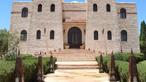 A large stone building with a central entrance, flanked by two towers, and a staircase leading up to the door. - Villa Riad Dharma (Essaouira)