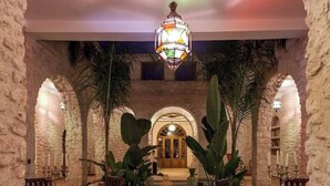 An interior with stone arches, a central fountain, and a tiled floor. - Villa Riad Dharma (Essaouira)