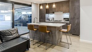 A modern kitchen with a central island, bar stools, and pendant lighting.