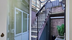 A narrow stairway with a metal railing leading to a brick wall.