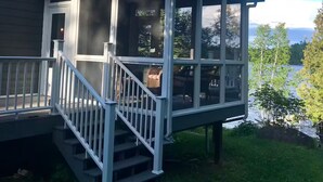 A house with a covered porch and a staircase leading to a deck. - Caribou Sunrise, Lakeside Cabin in the Northwoods! (Lutsen)