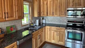 A kitchen with wooden cabinets, a stainless steel oven, and a dishwasher. - Caribou Sunrise, Lakeside Cabin in the Northwoods! (Lutsen)