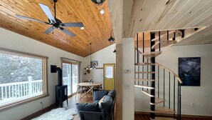 A modern interior with a wooden ceiling, a spiral staircase, a sofa, and a dining area. - Caribou Sunrise, Lakeside Cabin in the Northwoods! (Lutsen)