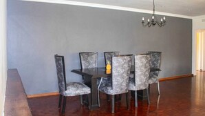 A dining area with a gray wall, a chandelier, and a wooden floor.