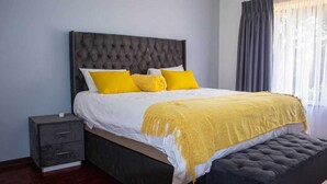 A bed with a tufted headboard, two bedside tables, and a bench at the foot of the bed.