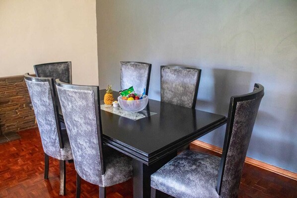 A dining table with six chairs, a bowl of fruit, and a small decorative item on the table.