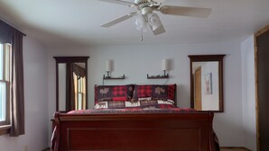 A bedroom with a wooden bed, a ceiling fan, a window with curtains, and a door. - Ranches, Lakes, Mountains & the Great Outdoors. Bring Your Horses Pasture Onsite (Helena)