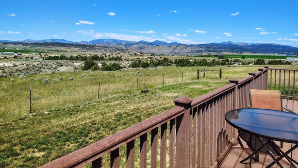 A patio with a table and chairs, overlooking a grassy field and distant mountains. - Ranches, Lakes, Mountains & the Great Outdoors. Bring Your Horses Pasture Onsite (Helena)