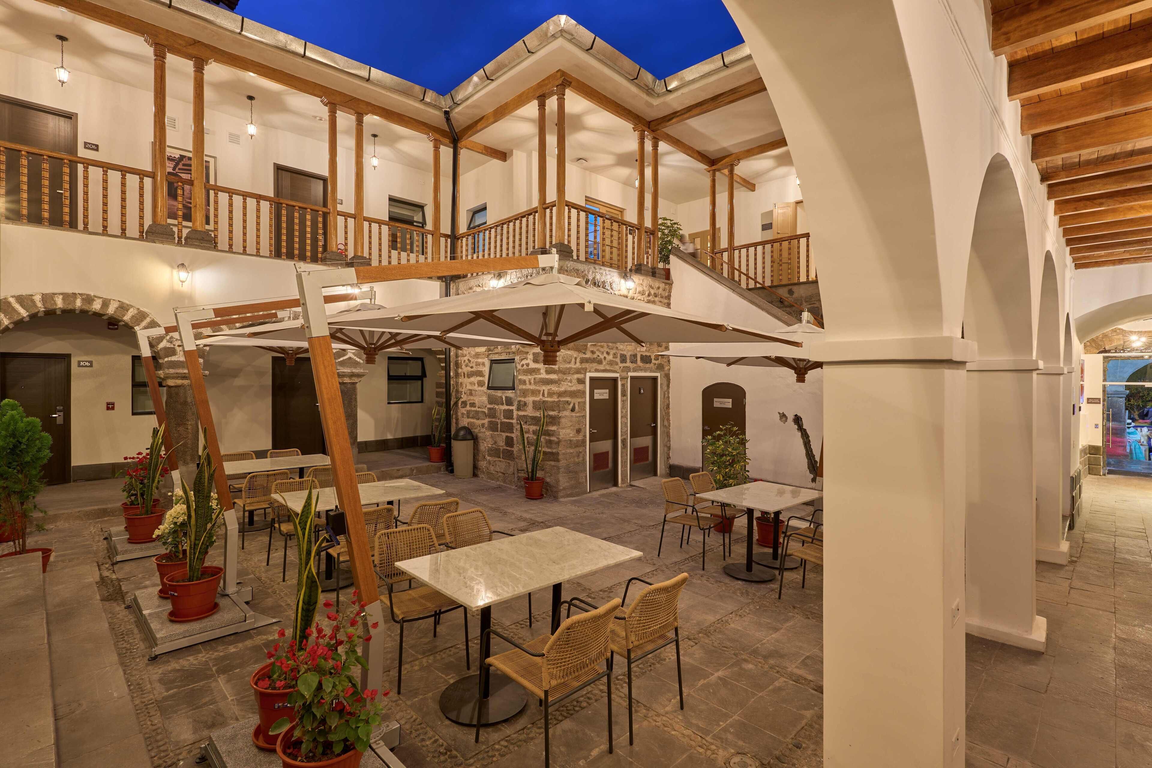 A spacious indoor courtyard with multiple seating areas, stone walls, and wooden beams.