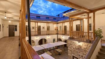 Un patio con mobiliario exterior, paredes de piedra y vigas de madera.