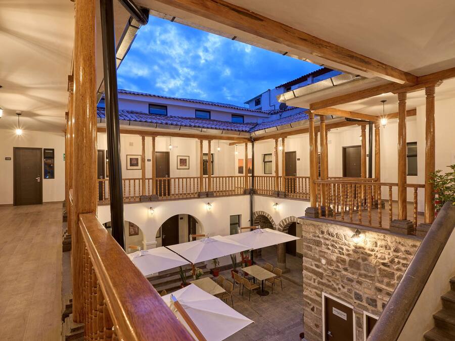 Un patio con mobiliario exterior, paredes de piedra y vigas de madera.