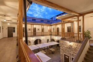 Un patio con mobiliario exterior, paredes de piedra y vigas de madera.