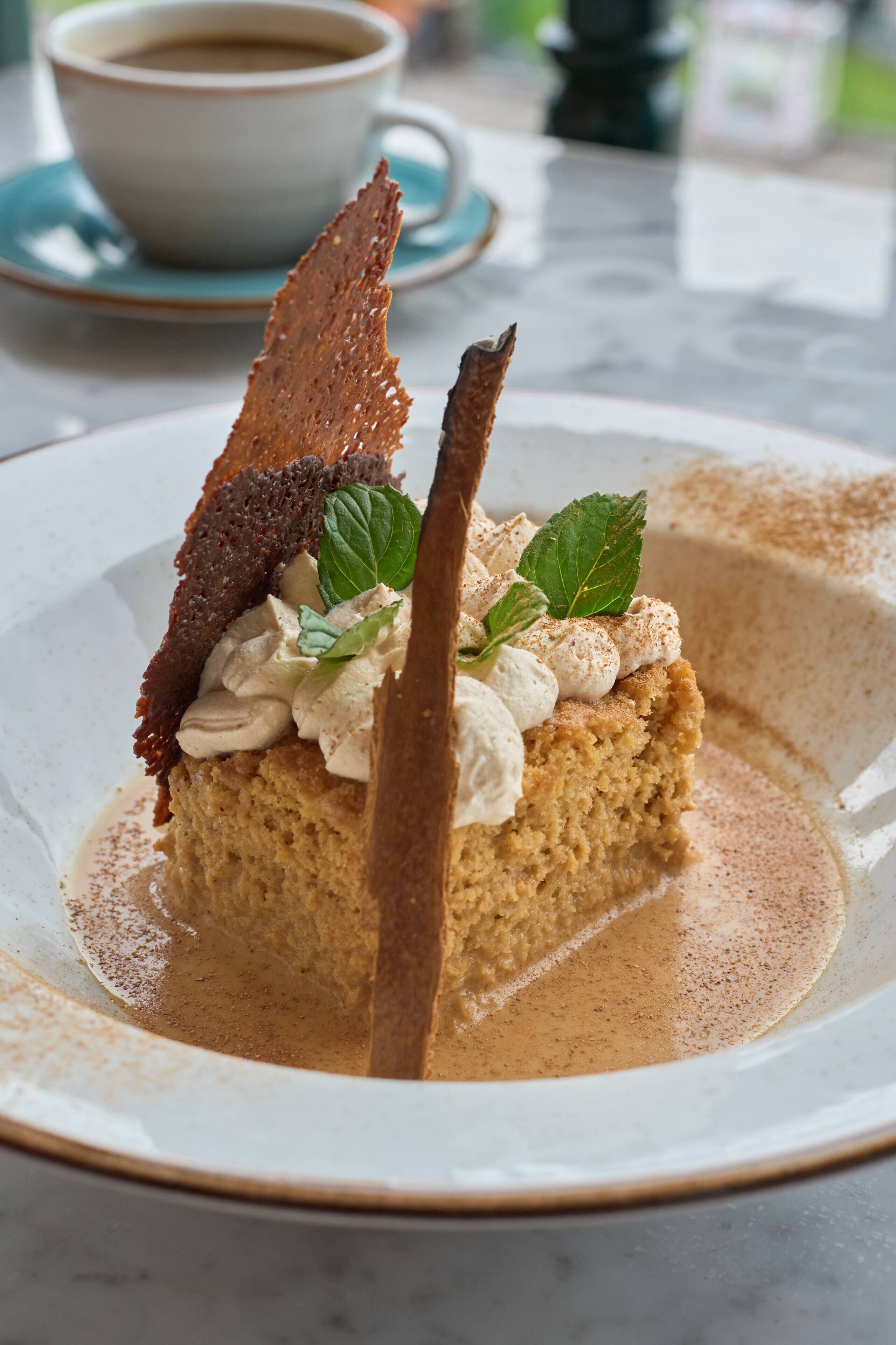 Un dessert présenté sur une assiette, avec une tasse de café en arrière-plan.