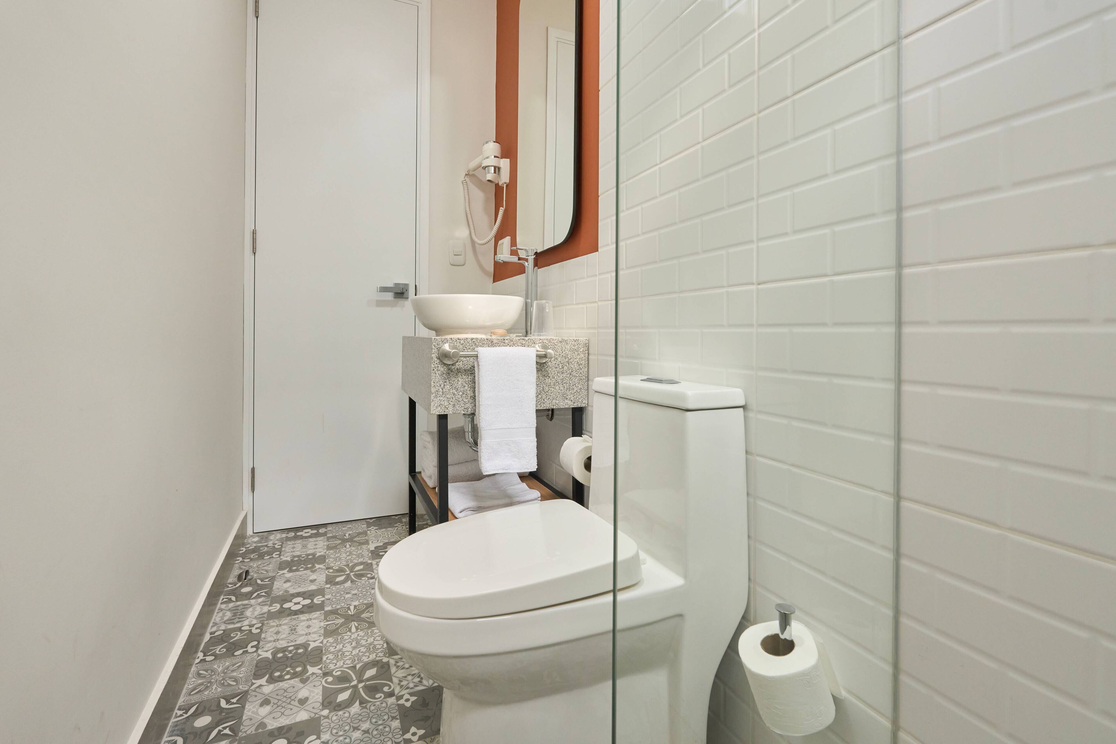 Un baño pequeño con inodoro, lavamanos y ducha.