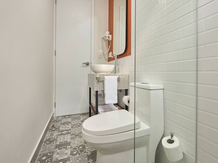 Un baño pequeño con inodoro, lavamanos y ducha.