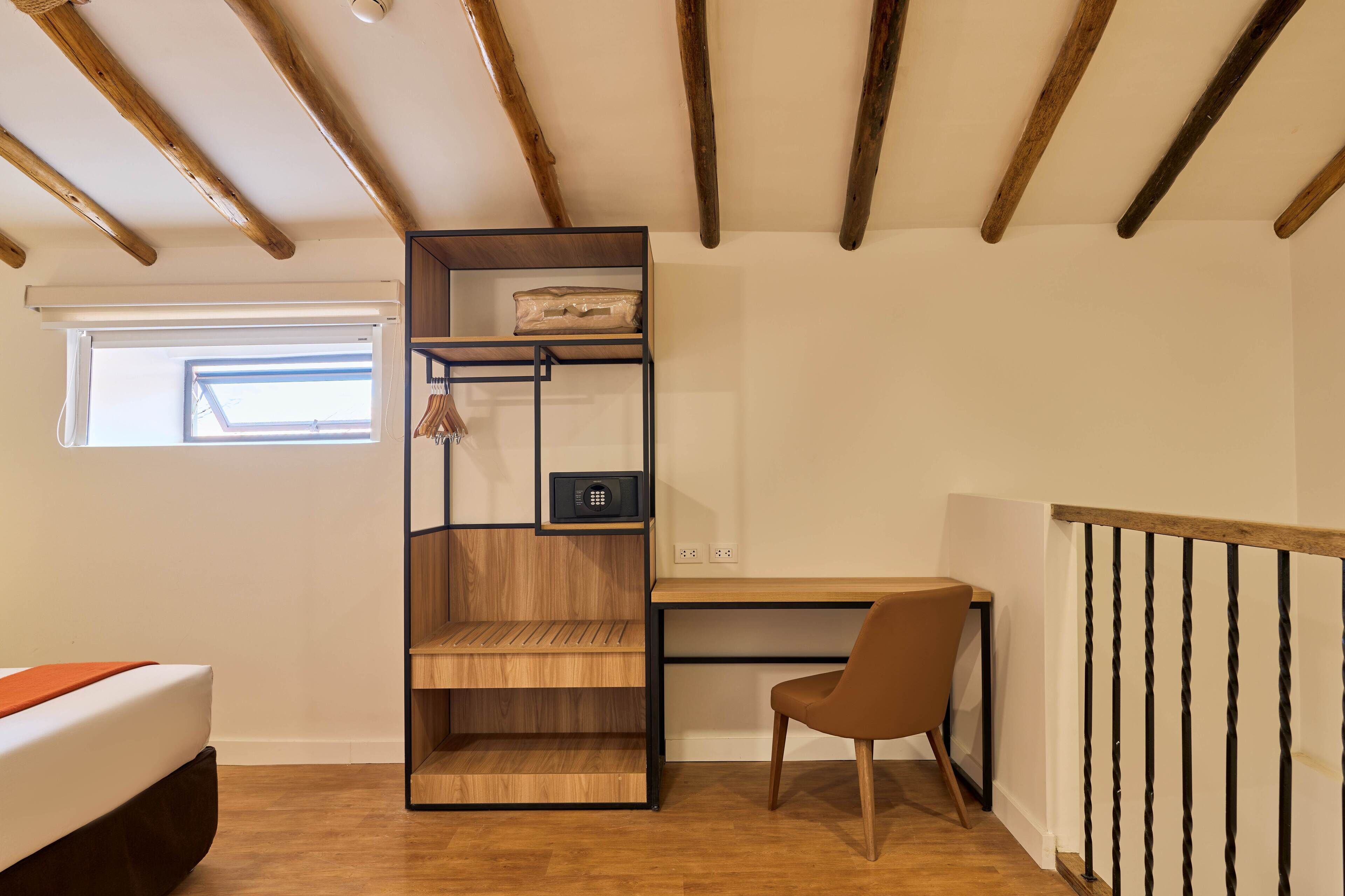 A room with a bed, a desk, a chair, a wooden shelving unit, and a window.