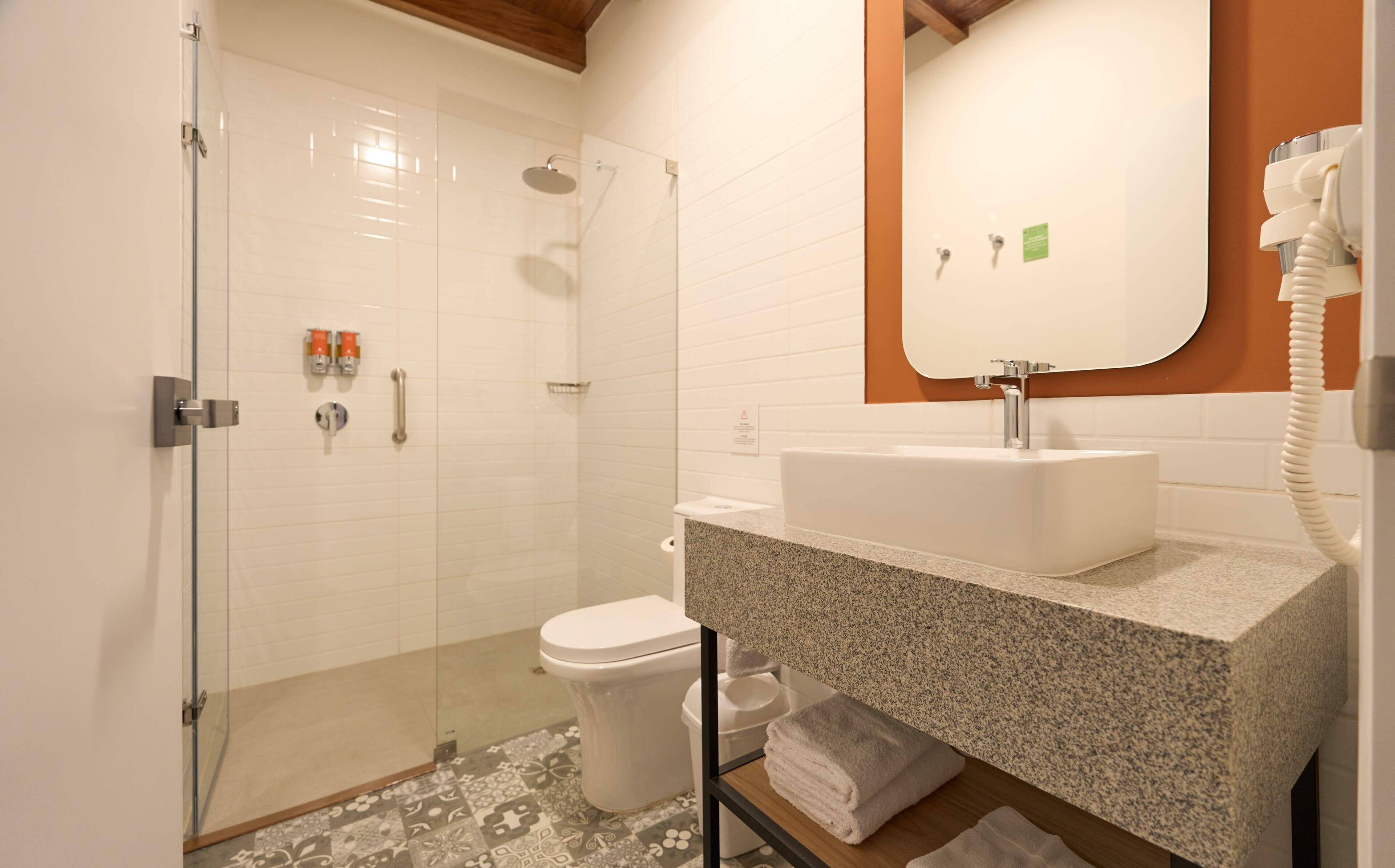 A modern bathroom with a glass-enclosed shower, a white toilet, and a granite countertop sink.