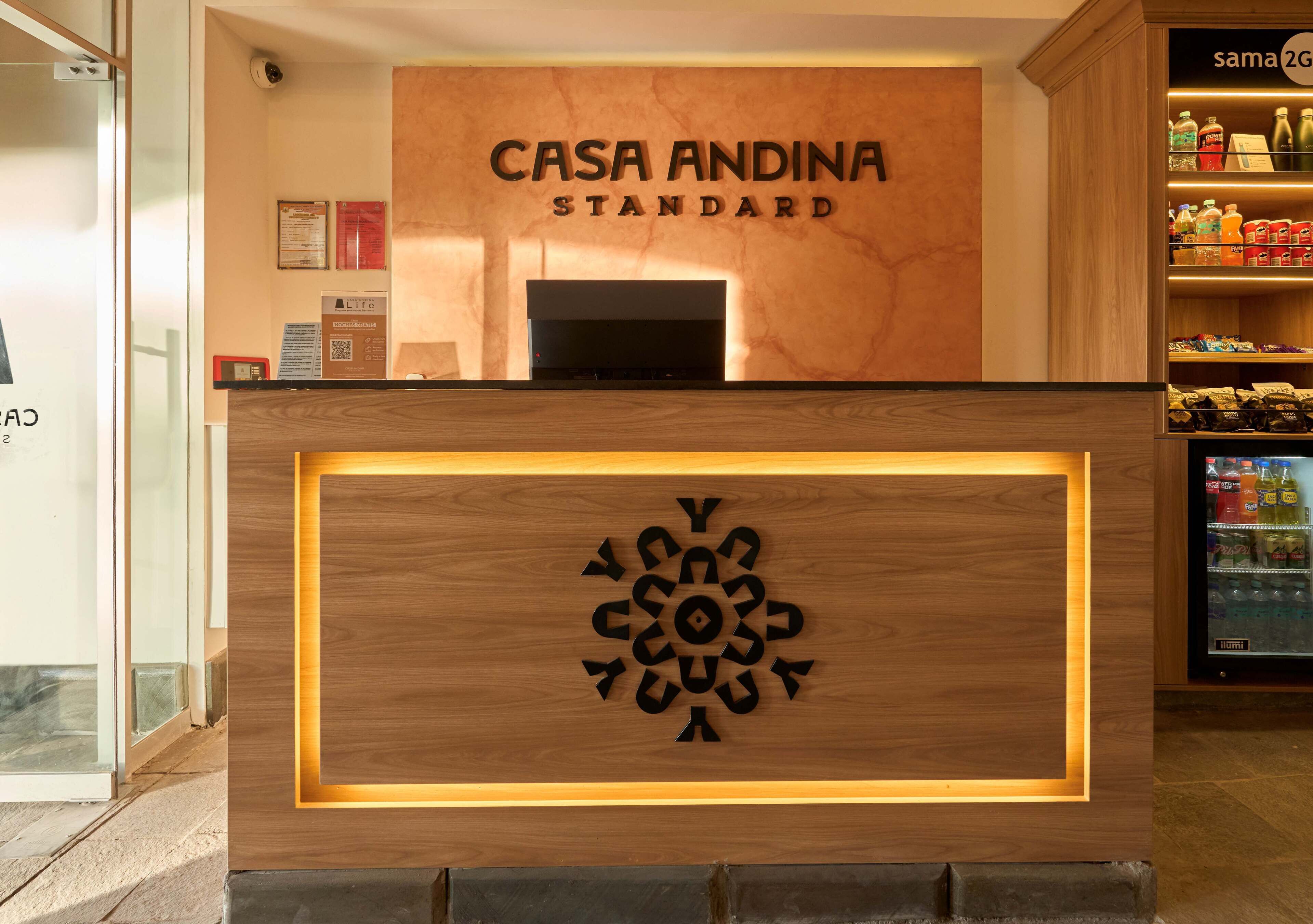 A reception desk with a wooden design and a sign that reads "CASA ANDINA STANDARD".