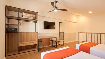 Habitación de hotel con cama, escritorio, silla, armario, ventilador de techo, televisión y barandilla de balcón.