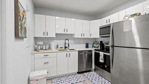 Een moderne keuken met witte kastjes, roestvrijstalen apparatuur, een vaatwasser en een koelkast.