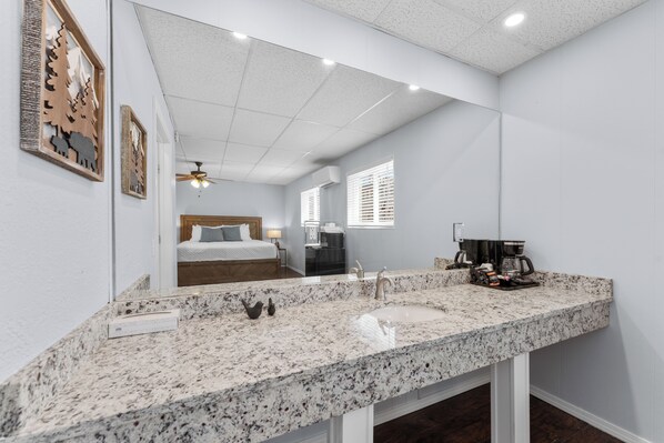 A modern bathroom with a granite countertop, a sink, and a mirror.
