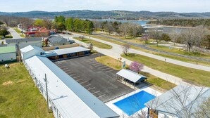 A large building with a parking lot, a covered outdoor seating area, and a view of a lake and mountains in the distance.