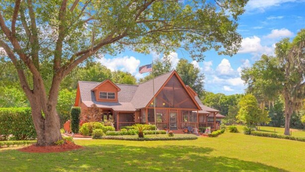A large, two-story house with a wrap-around porch, a large window, and a well-maintained lawn. - Captain's Room on Cabin on the Lake (Lake Helen)