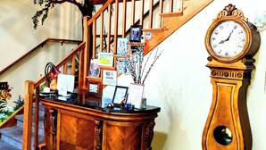 A wooden staircase with a clock and a reception desk. - Captain's Room on Cabin on the Lake (Lake Helen)