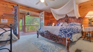 A wooden cabin bedroom with a canopy bed, a ceiling fan, and a view of the outdoors. - Captain's Room on Cabin on the Lake (Lake Helen)