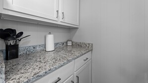 A kitchen with white cabinets, a granite countertop, and a coffee maker. - Come stay at this modern 2 bedroom suite, located close to Table Rock Lake and Silver Dollar City. (Branson)