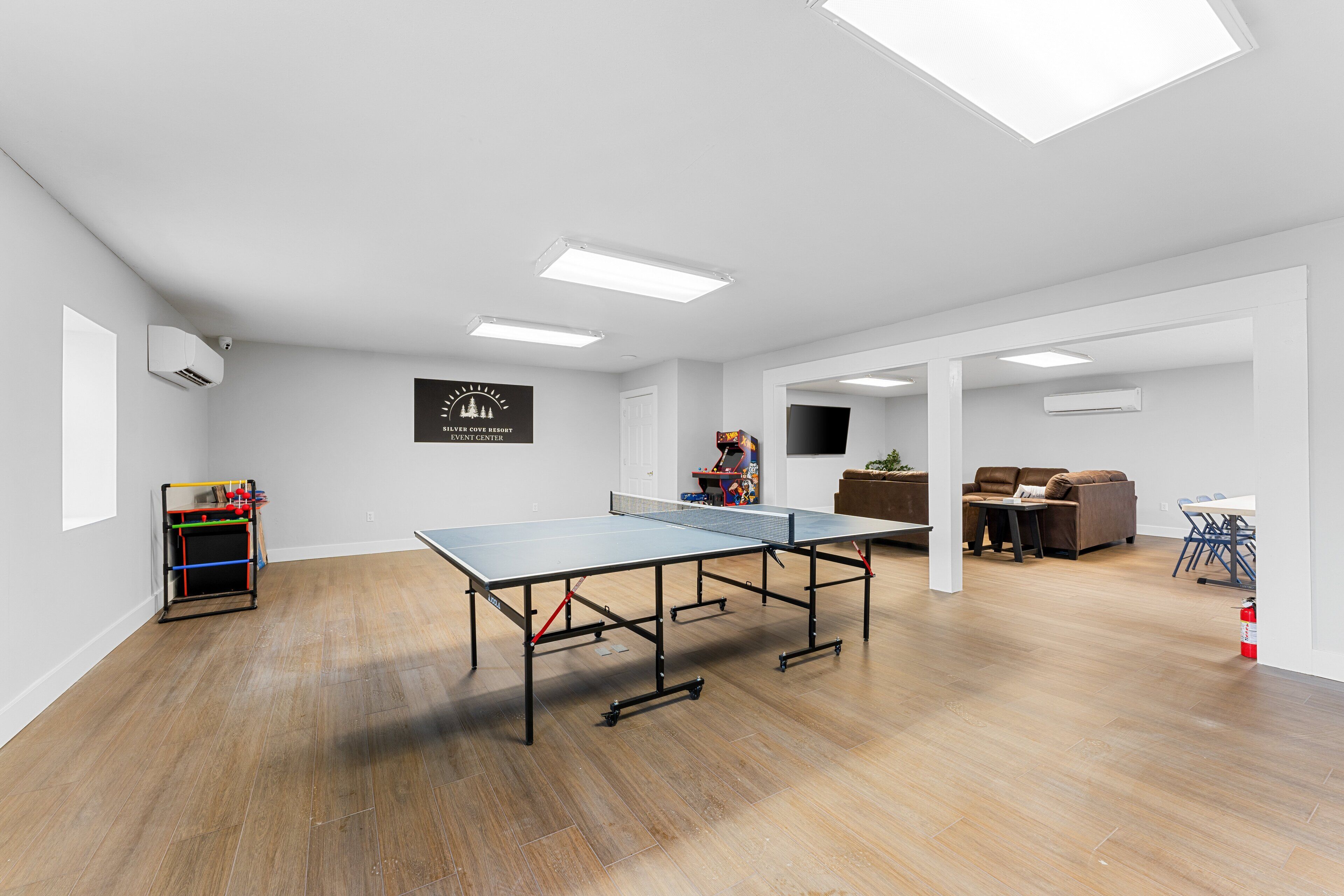 En rummelig stue med et pingpongbord, en bogreol og en sofa.