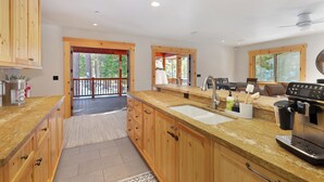 A modern kitchen with wooden cabinets, a large island, and a coffee machine.