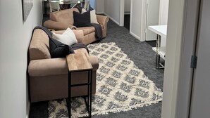 Una sala de estar moderna con un sofá color beige, una mesa de centro y un tapete estampado.