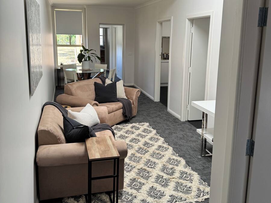 Una sala de estar moderna con un sofá color beige, una mesa de centro y un tapete estampado.