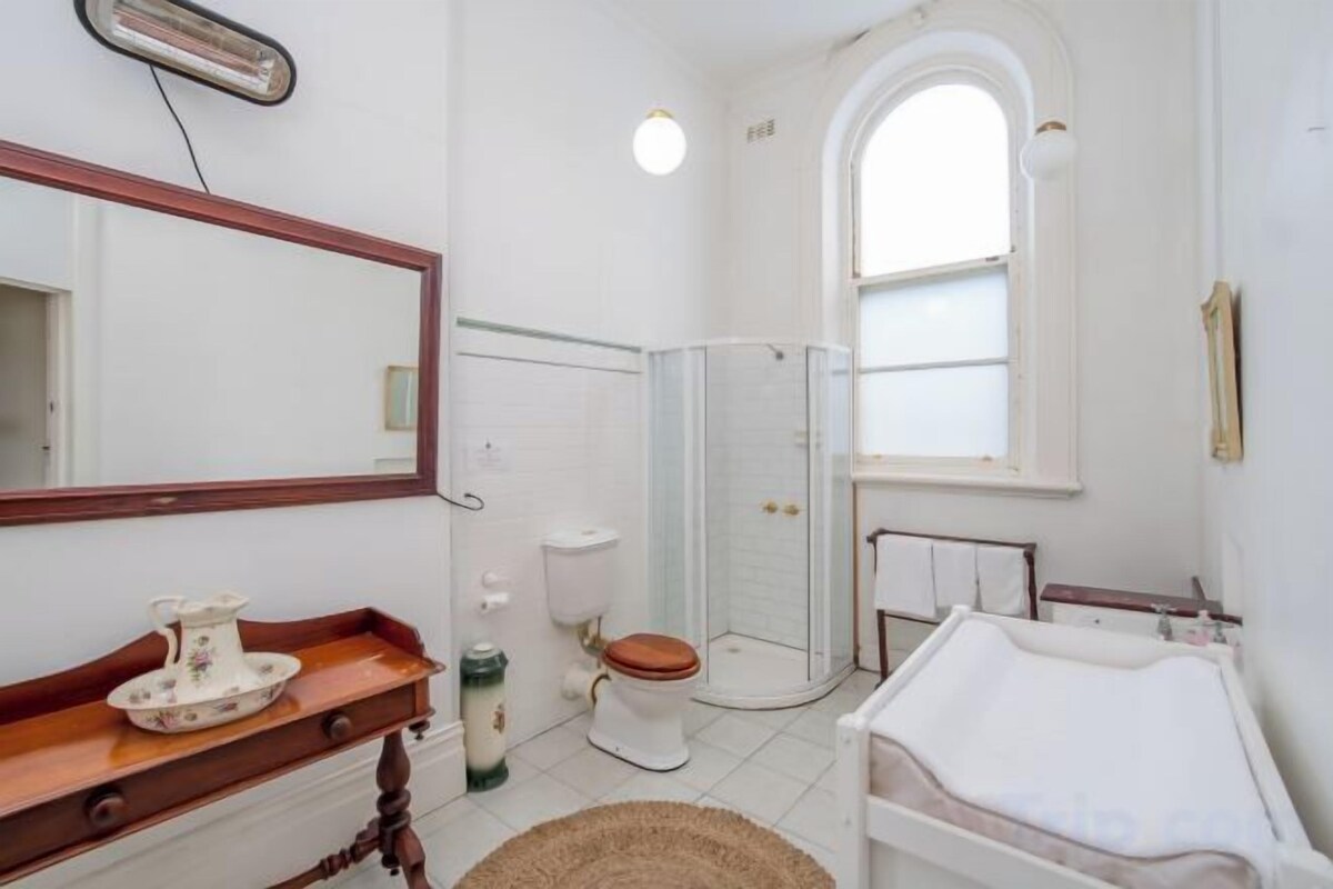 Une salle de bain avec un lavabo blanc, un meuble-lavabo en bois, des toilettes et un espace douche.
