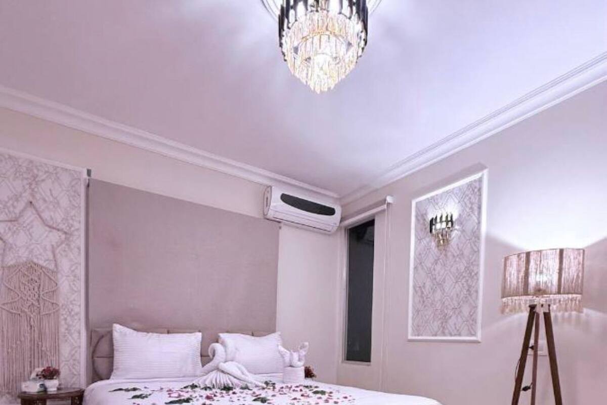 Ein Schlafzimmer mit einem großen Bett, einer Kristallleuchtre, einer Klimaanlage und einer Stehlampe.