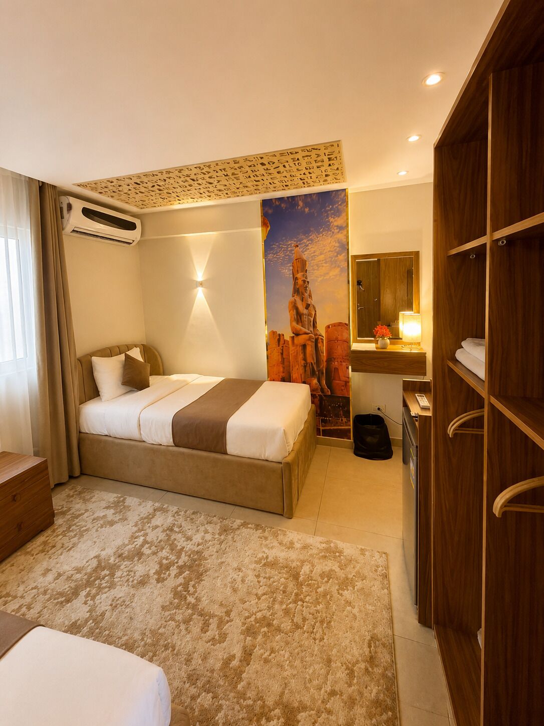 A hotel room with a large bed, a desk, a wardrobe, and a mural on the wall.