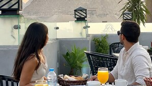 A dining table with food and drinks, a view of the pyramids, and a plant.