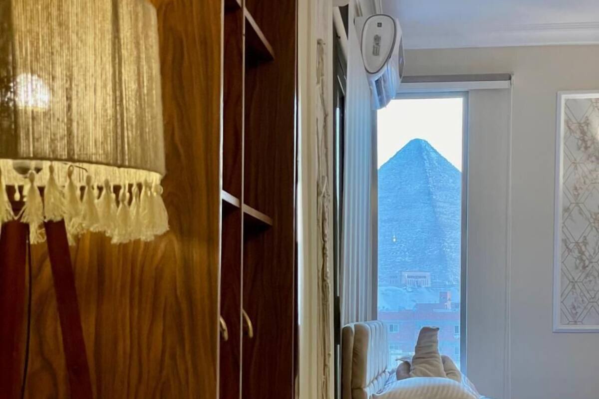 Ein Schlafzimmer mit einem Bett, einem Nachttisch, einer Lampe und einem Fenster mit Bergblick.