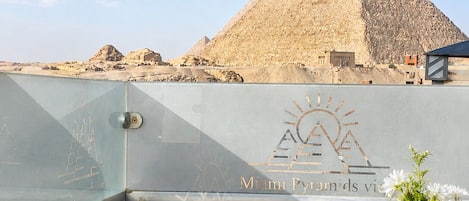Una mesa de desayuno con diversas opciones, un vaso de zumo de naranja y vistas a las Pirámides de Giza.