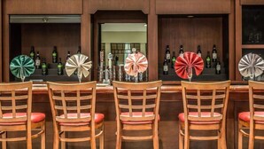 A bar area with wooden chairs and a counter displaying bottles. - Regency Inn and Suites - Non Smoking King (New London)