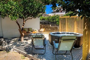 Une terrasse avec deux chaises, un jacuzzi et une table avec des boissons.