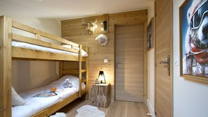 A bunk bed room with a wooden ceiling, a door, and a painting on the wall.