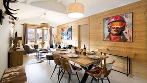 A modern dining area with a wooden table set for six, surrounded by chairs with a cowhide pattern.