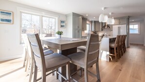Een moderne keuken met een centraal eiland, houten stoelen en een eettafel.