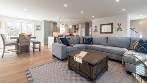 Een moderne woonkamer met een modulaire bank, een houten salontafel en een eethoek met stoelen en een tafel.