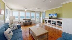 A living room with a wooden coffee table, blue sofa, and a television on a white entertainment unit.
