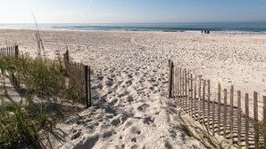 A sandy beach with wooden fences and sparse vegetation.