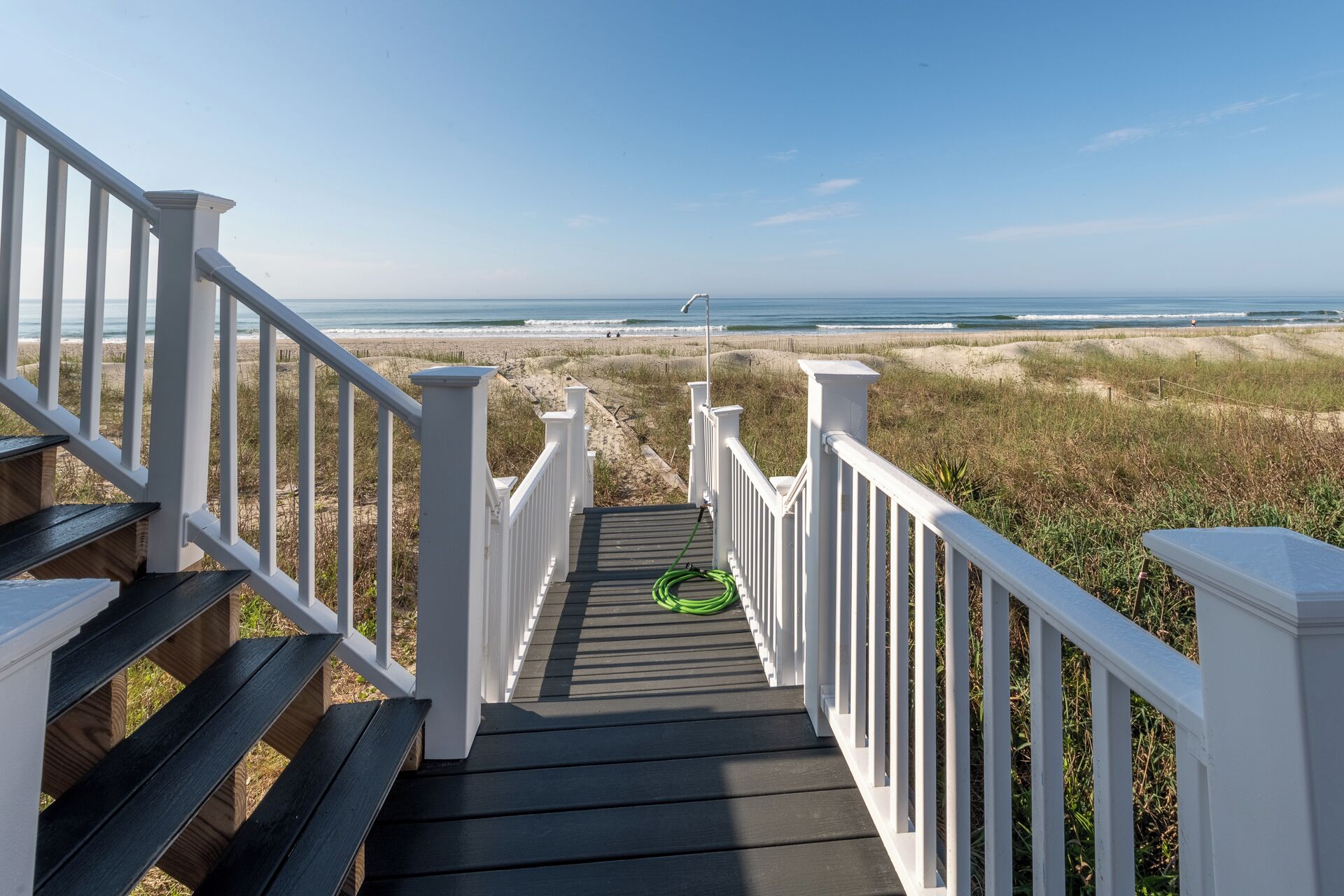 A wooden staircase leading to a beach with white railings.