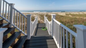 A wooden staircase leading to a beach with white railings.